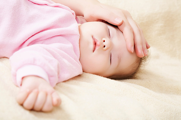 寝ている幼児の顔を撫でる手